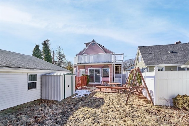 rear view of house with a storage shed, fence, and an outbuilding