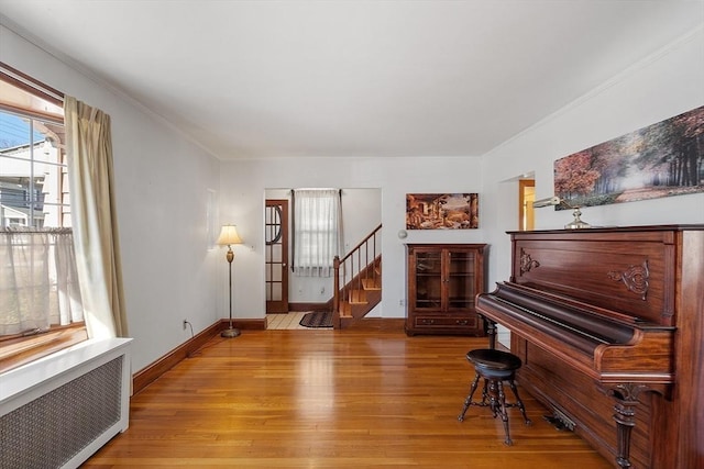 sitting room featuring radiator heating unit, stairs, ornamental molding, and wood finished floors