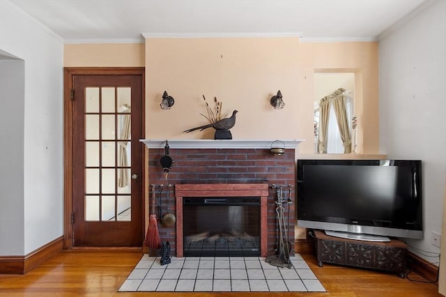 living room featuring ornamental molding, a brick fireplace, baseboards, and wood finished floors