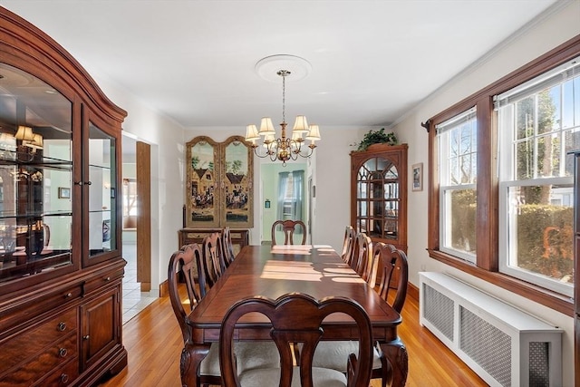 dining area featuring radiator, an inviting chandelier, light wood-type flooring, and crown molding