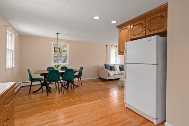 dining space featuring light wood finished floors, a wealth of natural light, a chandelier, and baseboards
