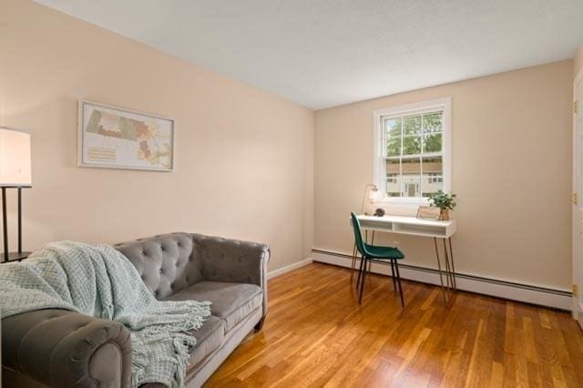 sitting room with wood finished floors, baseboards, and a baseboard heating unit