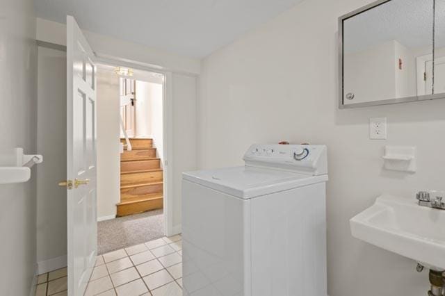 laundry room with baseboards, light tile patterned flooring, a sink, washer / dryer, and laundry area
