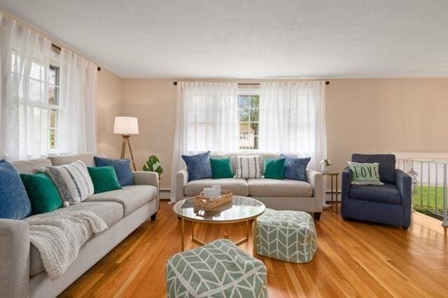 living area with a baseboard heating unit and wood finished floors
