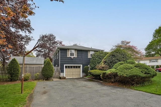 view of front of home with aphalt driveway, fence, and a garage