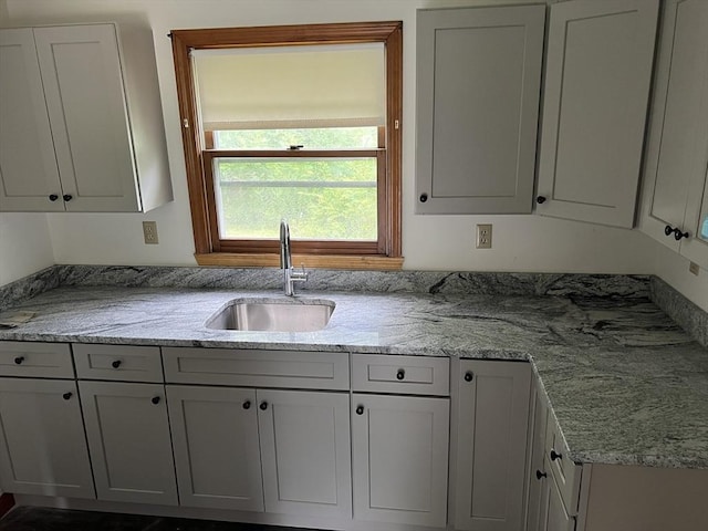 kitchen with a sink and light stone countertops