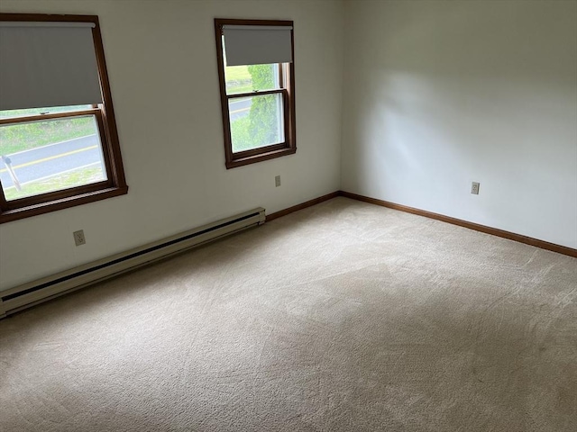 carpeted empty room featuring a baseboard heating unit and baseboards