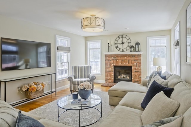 living room featuring a brick fireplace, wood finished floors, and baseboards