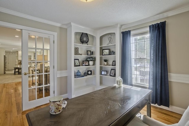 home office featuring french doors, a textured ceiling, crown molding, and light wood finished floors