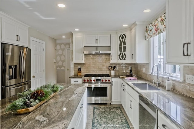 kitchen with light stone counters, a sink, under cabinet range hood, appliances with stainless steel finishes, and white cabinetry