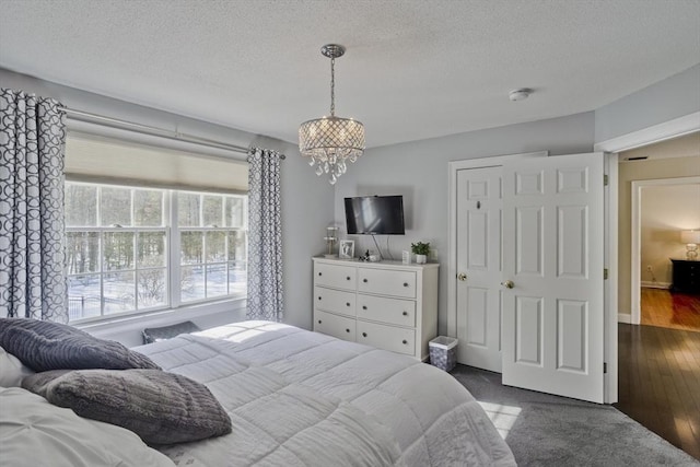 bedroom featuring dark wood-style floors, a textured ceiling, and a chandelier