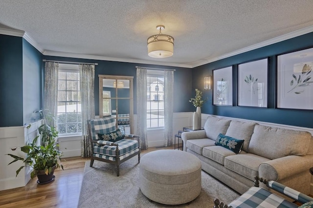 living room featuring a wealth of natural light, a wainscoted wall, wood finished floors, and ornamental molding