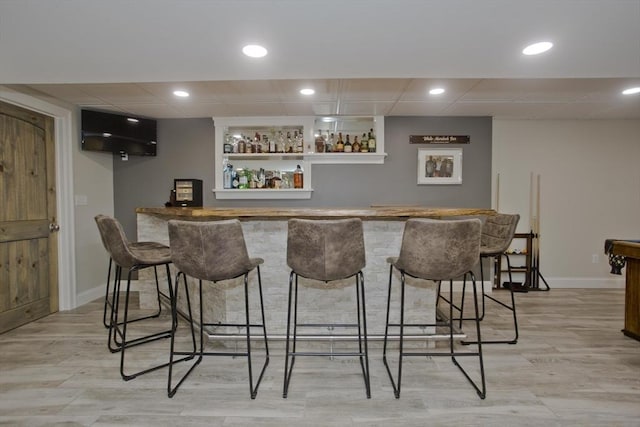 bar with recessed lighting, light wood-style floors, baseboards, and indoor bar