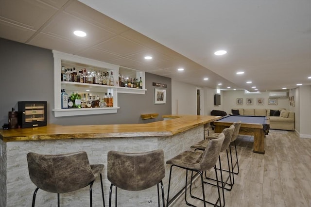 bar with recessed lighting, bar, wood finished floors, and a wall unit AC