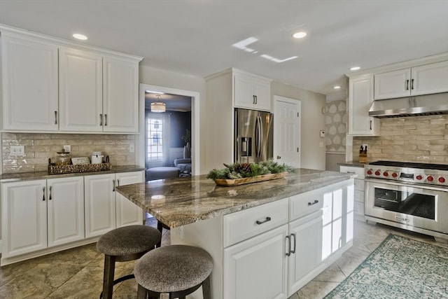 kitchen with under cabinet range hood, stainless steel appliances, white cabinets, and dark stone counters