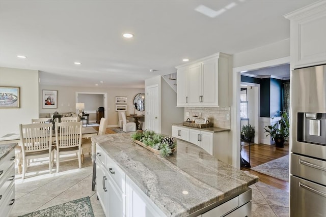 kitchen featuring decorative backsplash, white cabinets, recessed lighting, and stainless steel refrigerator with ice dispenser