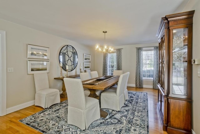 dining space with baseboards, an inviting chandelier, and wood finished floors