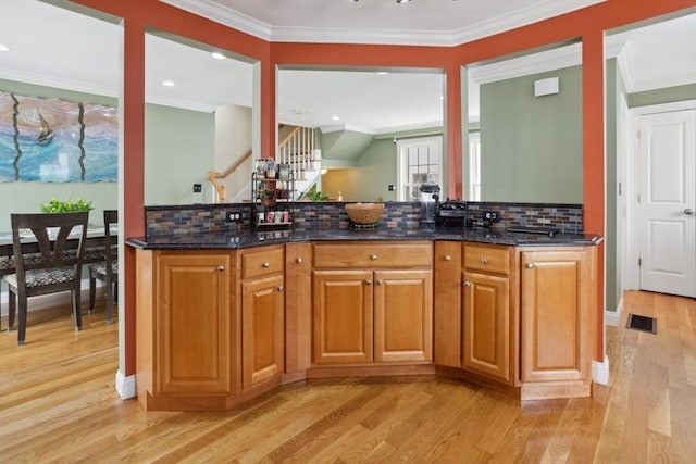 224 Grove St Unit 2, Waltham, MA 02453 - kitchen with light wood-style flooring, ornamental molding, dark stone countertops, backsplash, and brown cabinetry