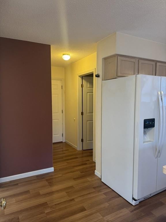 kitchen featuring dark hardwood / wood-style floors, light brown cabinetry, a textured ceiling, and white fridge with ice dispenser