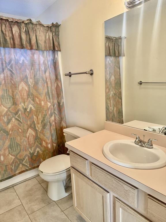 full bathroom with tile patterned flooring, vanity, shower / tub combo, and toilet