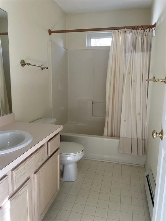 full bathroom with vanity, a baseboard heating unit, toilet, and shower / bath combo with shower curtain