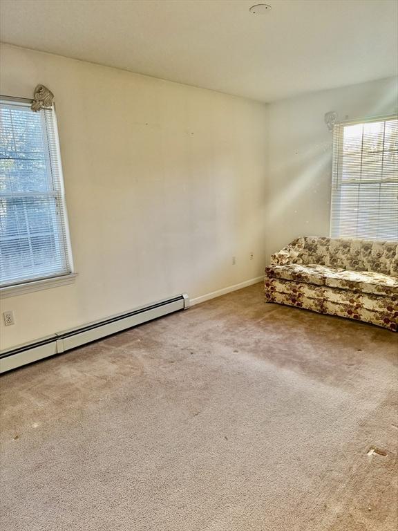 unfurnished room with a baseboard heating unit and carpet floors