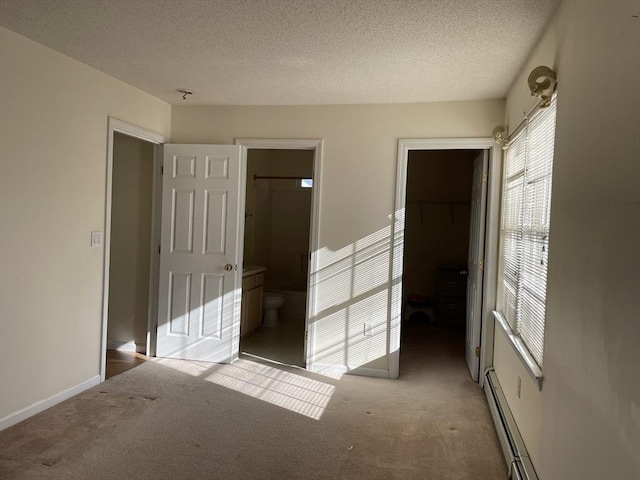 unfurnished bedroom with carpet floors, a spacious closet, ensuite bath, and a closet