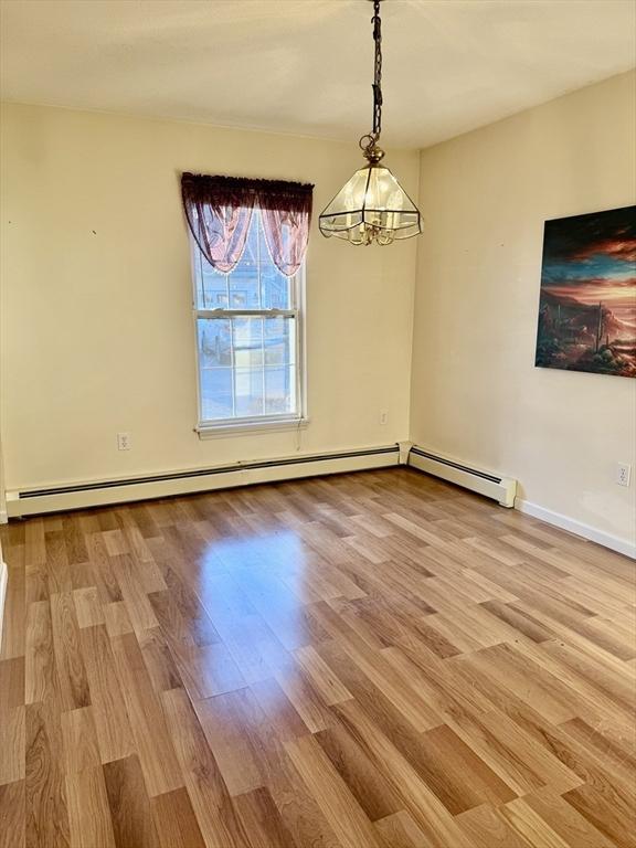 unfurnished dining area with a baseboard heating unit, light hardwood / wood-style floors, and a notable chandelier