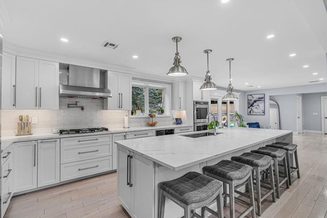 34 Cedar St, Hopkinton, MA 01748 - kitchen with stainless steel appliances, light wood-style floors, wall chimney exhaust hood, white cabinetry, and recessed lighting