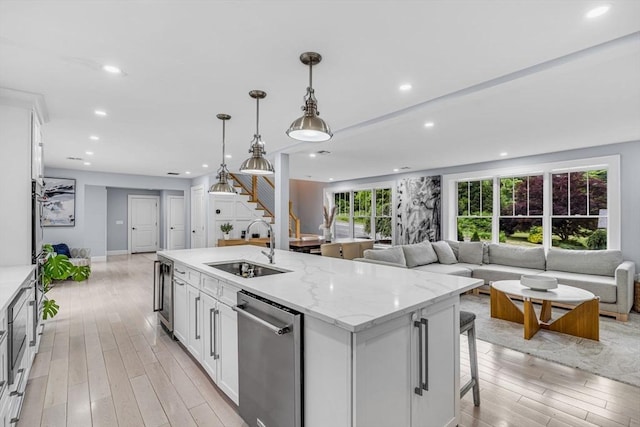 34 Cedar St, Hopkinton, MA 01748 - kitchen featuring dishwasher, open floor plan, light wood-style flooring, white cabinetry, and a center island with sink