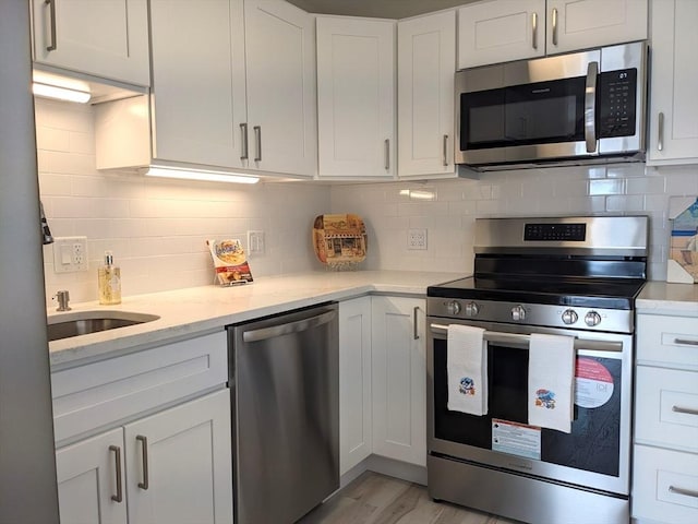 179 N End Blvd Unit A, Salisbury, MA 01952 - kitchen with appliances with stainless steel finishes, decorative backsplash, light wood finished floors, light stone counters, and white cabinetry