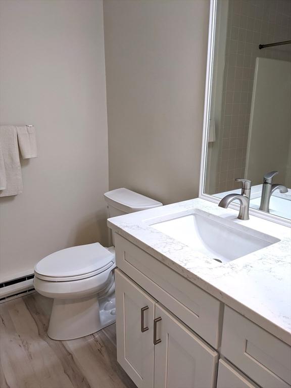 179 N End Blvd Unit A, Salisbury, MA 01952 - full bath with vanity, a baseboard heating unit, toilet, and wood finished floors