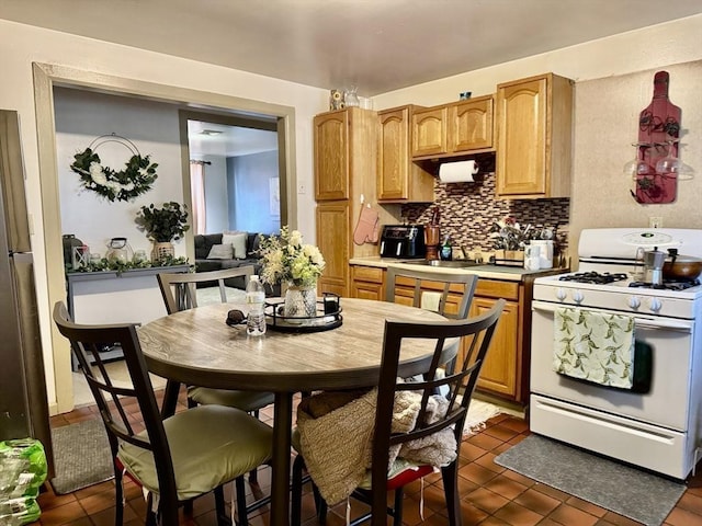 kitchen with white gas stove, backsplash, and light countertops