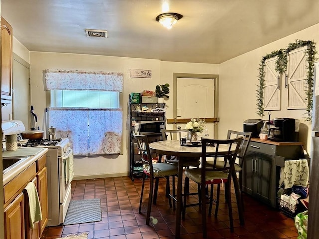 dining space featuring visible vents, baseboards, and dark tile patterned flooring