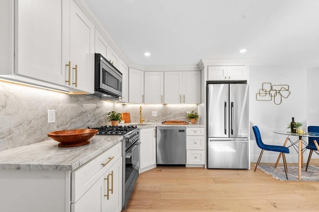 kitchen featuring backsplash, white cabinetry, light wood-type flooring, stainless steel appliances, and light stone counters