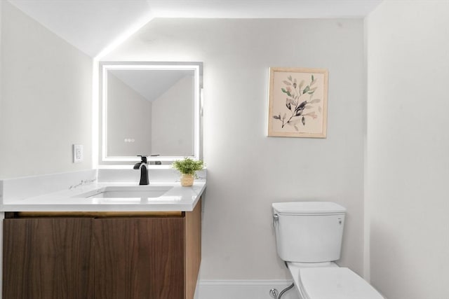 bathroom with toilet, vanity, and vaulted ceiling