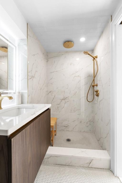 bathroom featuring vanity, a tile shower, and tile patterned flooring