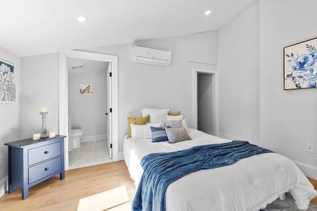 bedroom with ensuite bathroom, light hardwood / wood-style flooring, lofted ceiling, and a wall mounted AC