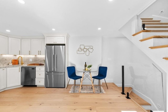 kitchen with tasteful backsplash, white cabinets, stainless steel fridge, and black dishwasher