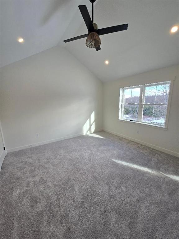 empty room with vaulted ceiling, carpet floors, and ceiling fan