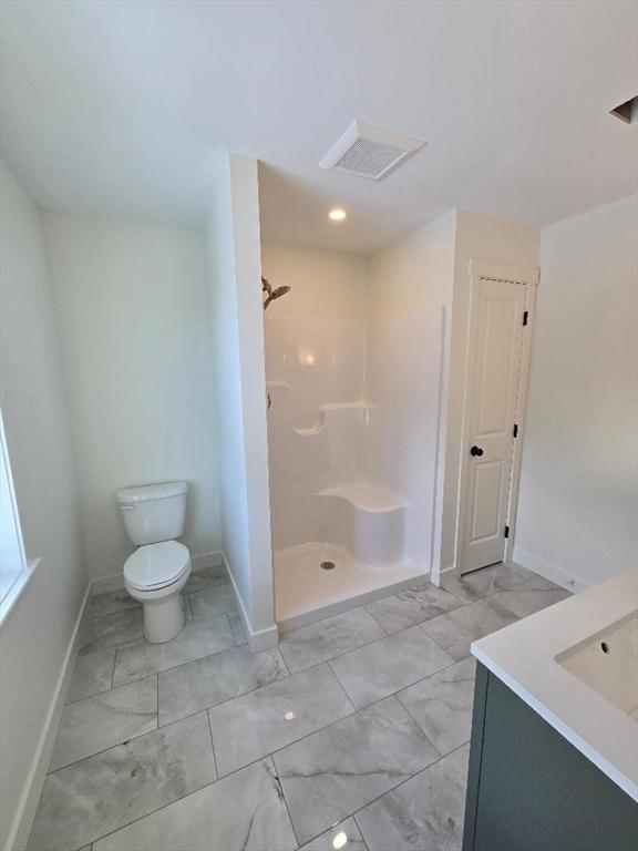 bathroom with walk in shower, vanity, and toilet