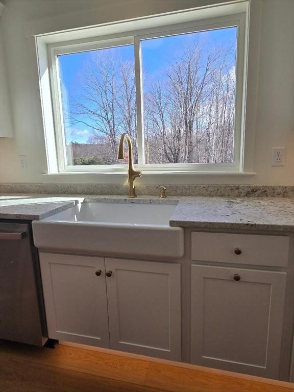 room details with dishwasher, light stone countertops, sink, and white cabinets