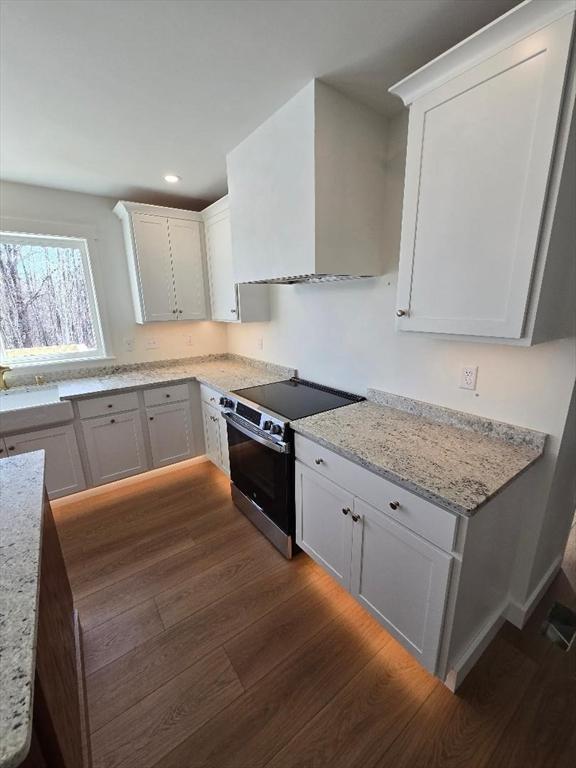 kitchen featuring white cabinetry, wall chimney range hood, dark wood-type flooring, and stainless steel range with electric cooktop