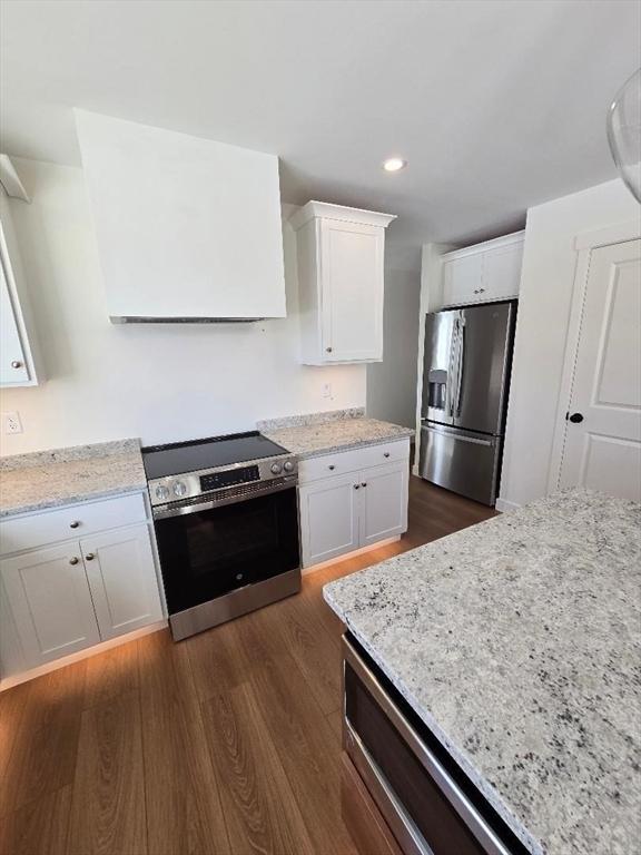 kitchen featuring stainless steel appliances, white cabinetry, light stone countertops, and dark hardwood / wood-style floors