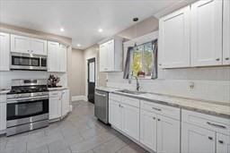 kitchen with white cabinetry, stainless steel appliances, sink, and light tile patterned floors