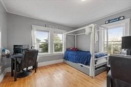 bedroom with multiple windows, wood-type flooring, and ornamental molding