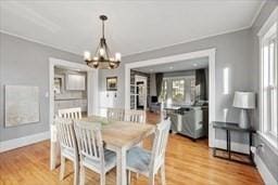 dining area featuring a healthy amount of sunlight, light wood-type flooring, and a notable chandelier