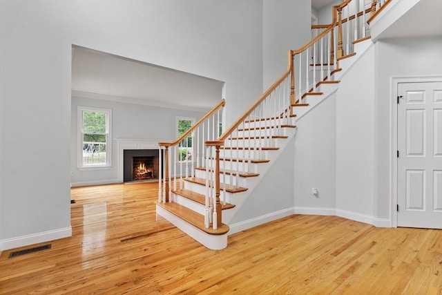 453 Forest St, North Andover, MA 01845 - staircase featuring wood finished floors, a warm lit fireplace, and a high ceiling
