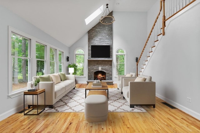 453 Forest St, North Andover, MA 01845 - living room featuring hardwood / wood-style flooring, a skylight, high vaulted ceiling, and a stone fireplace