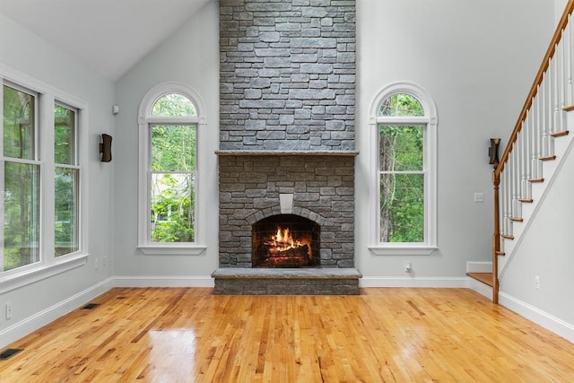 453 Forest St, North Andover, MA 01845 - unfurnished living room featuring high vaulted ceiling, plenty of natural light, hardwood / wood-style floors, stairs, and a stone fireplace